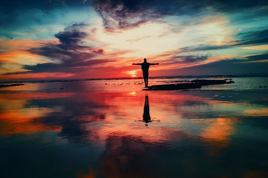 person with arms outstretched on a beach