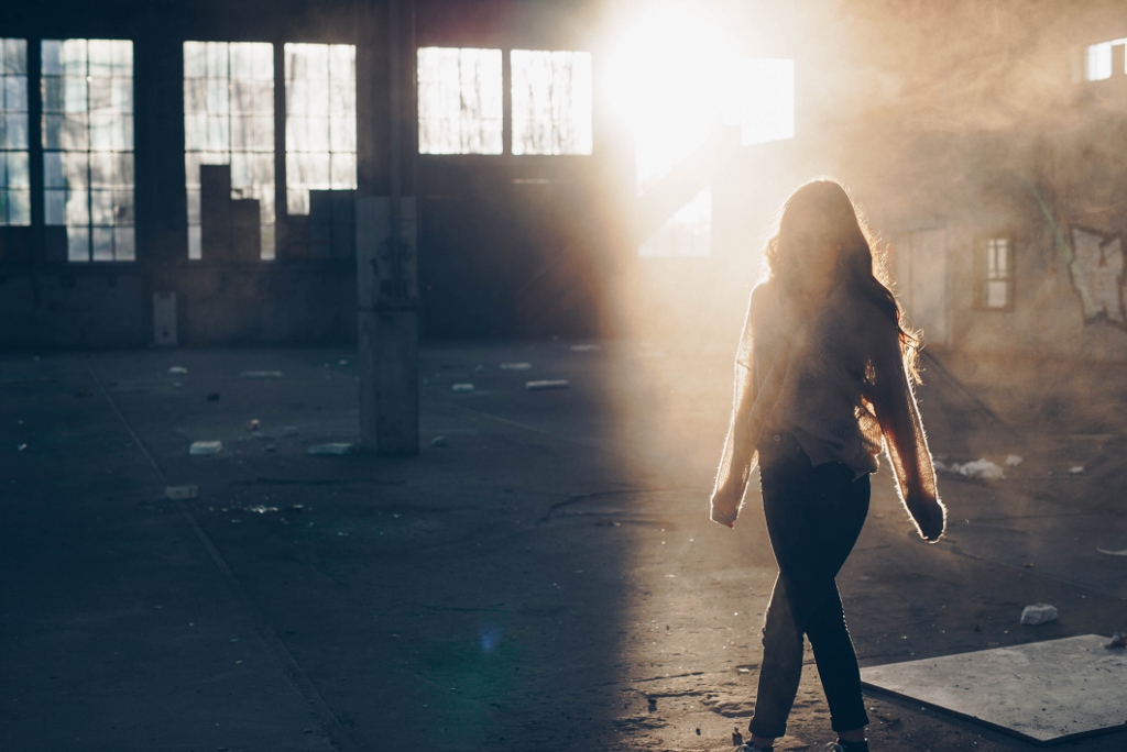 Woman walking in warehouse with light shining on her